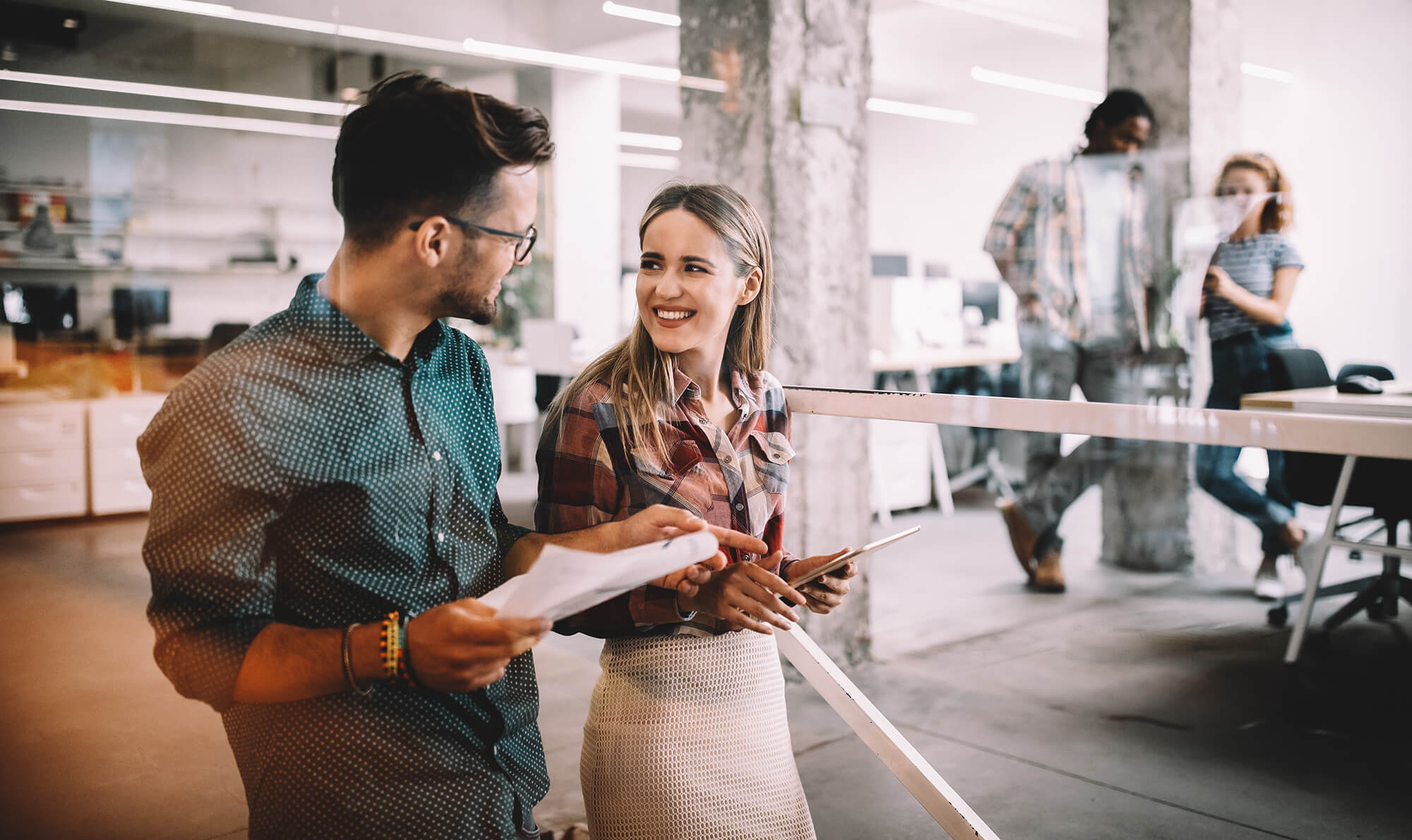 Two young professionals reviewing notes in a modern office building