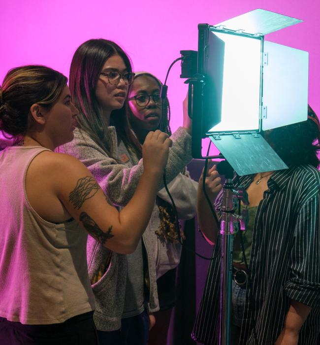 Three students looking at light settings on a film set